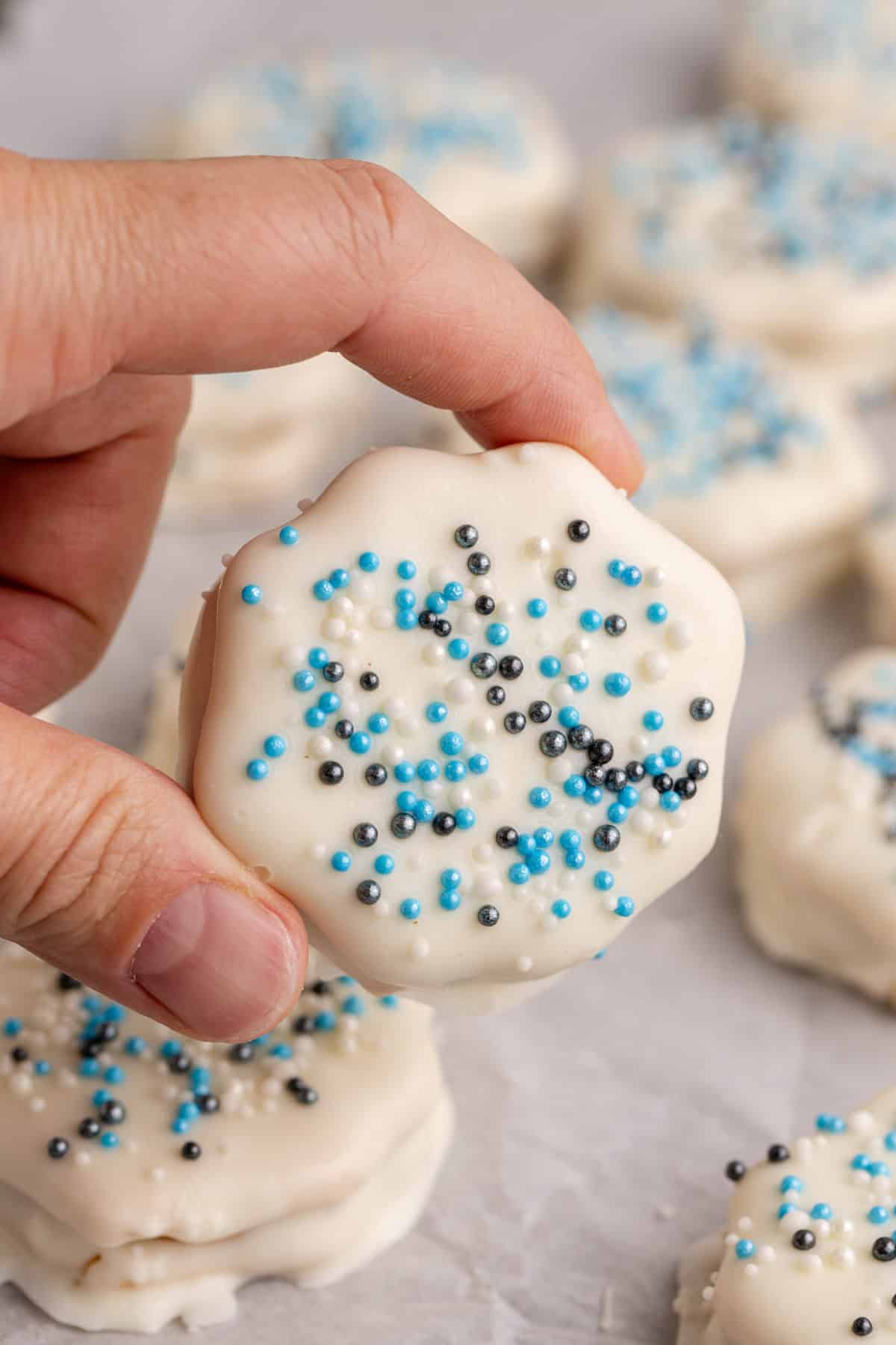 White Chocolate Ritz Cracker Cookies in the background and one being picked up
