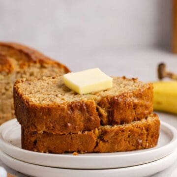 Banana Bread slices stacked on a plate with a pat of butter
