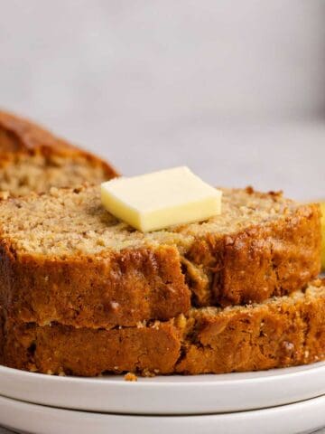 Banana Bread slices stacked on a plate with a pat of butter