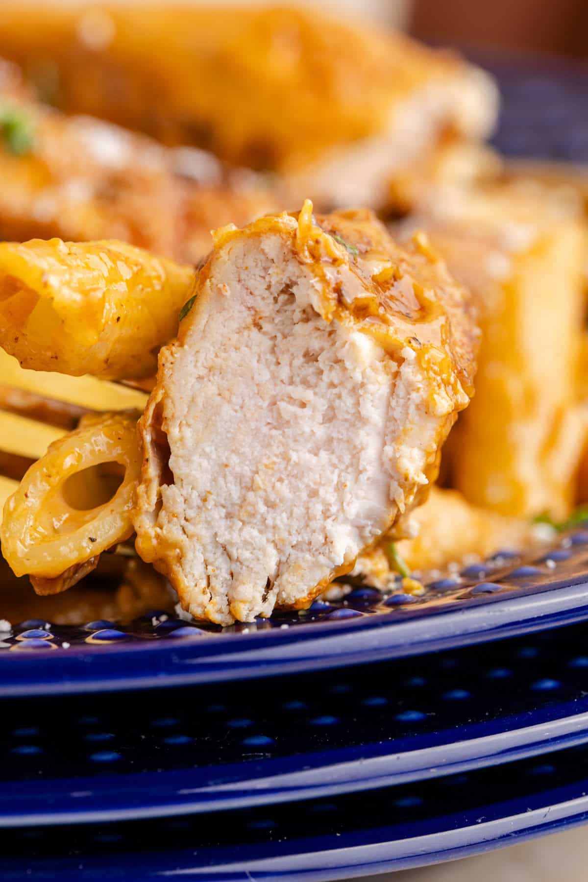 Bang Bang Chicken Pasta served in a blue bowl up close to see a cut piece of juicy chicken