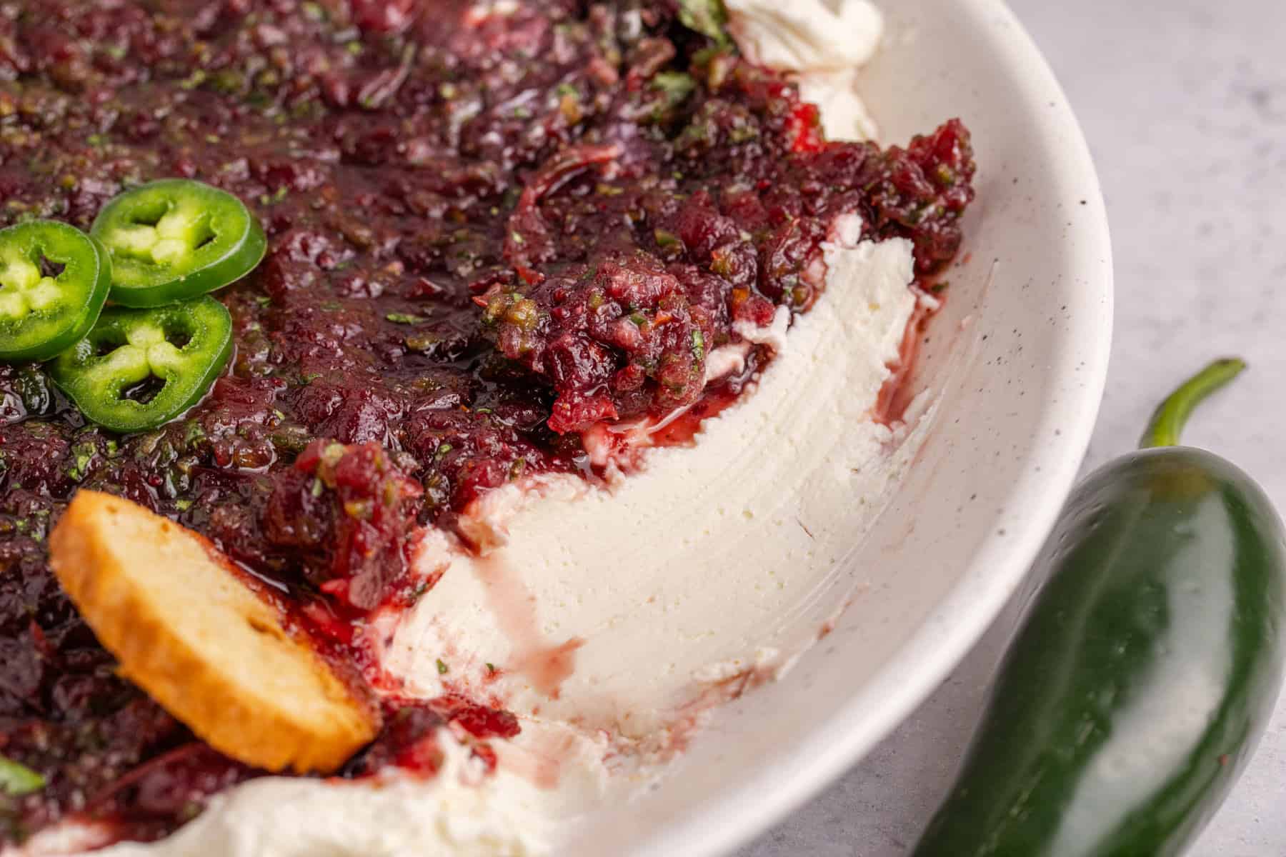 Cranberry Jalapeño Dip close up in a bowl with a scoop taken