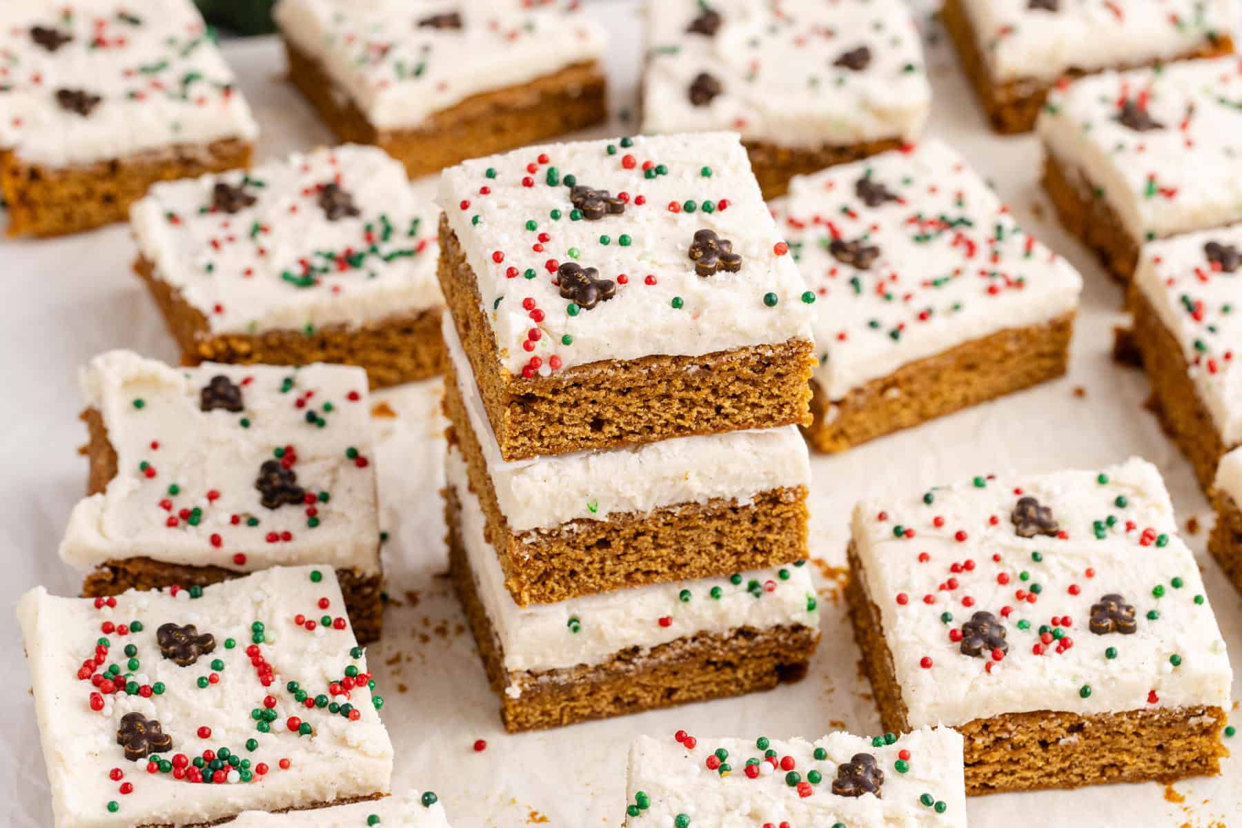Gingerbread Cookies Bars with Icing and sprinkles on parchment paper stacked